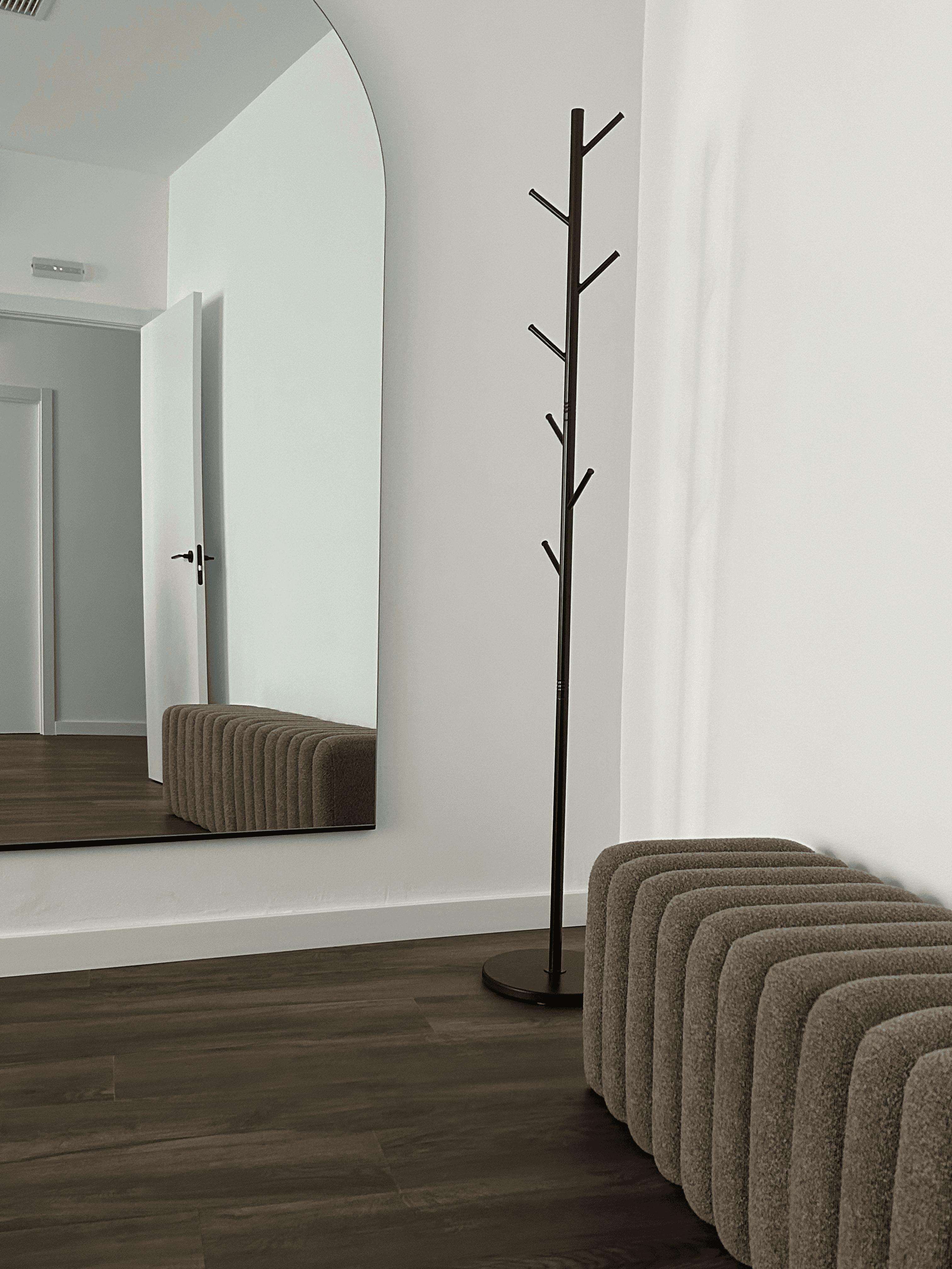 Zona de espera con espejo en arco y banco bouclé en Senara Studio